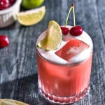 glass wtih cherry cocktail and limes