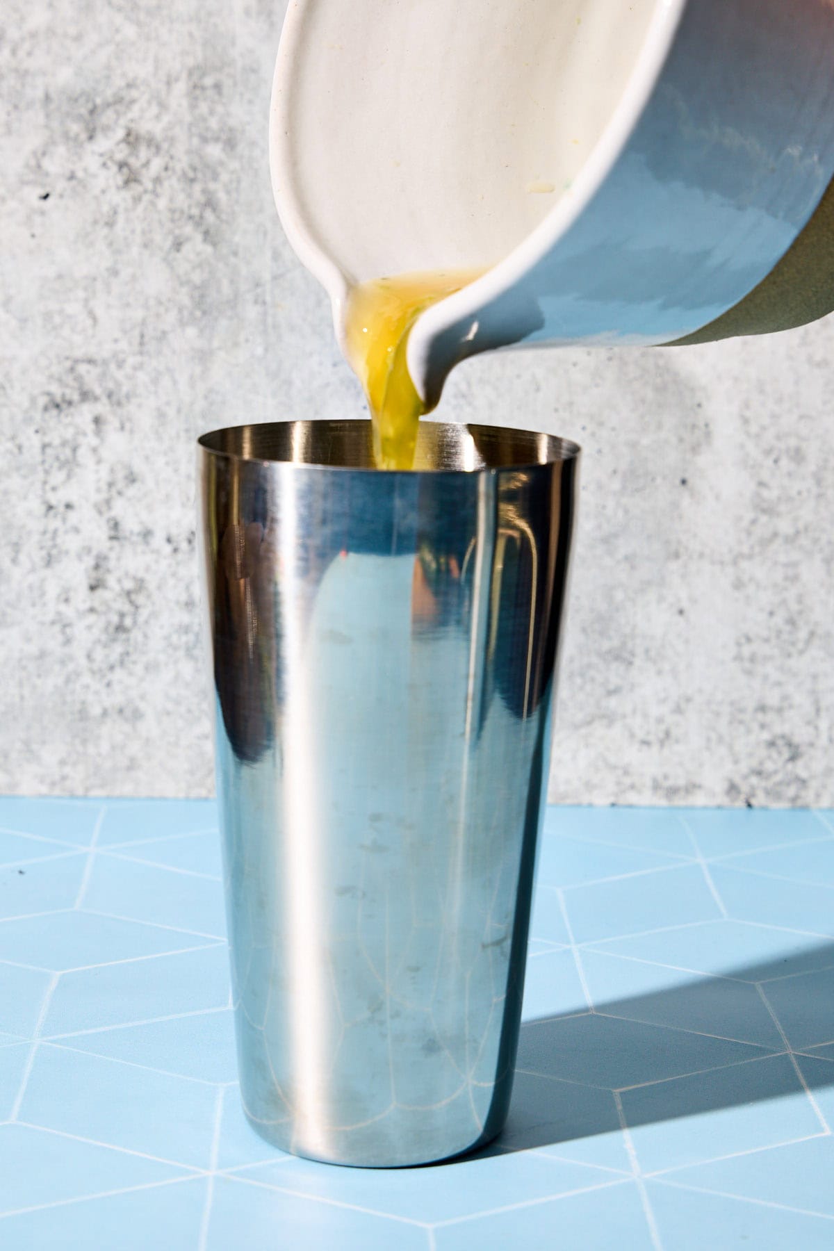 cucumber mixture being poured into a cocktail shaker