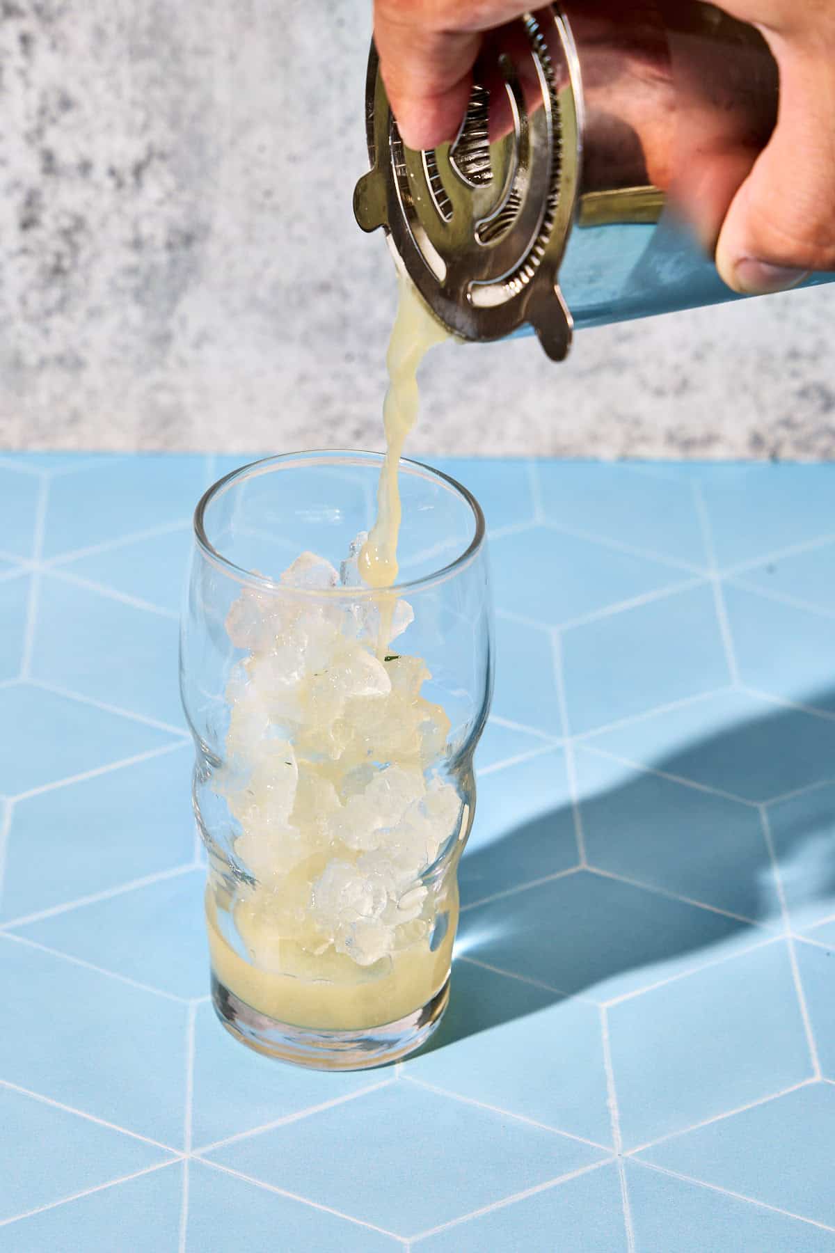 cucumbver cocktail being strained into a glass of ice