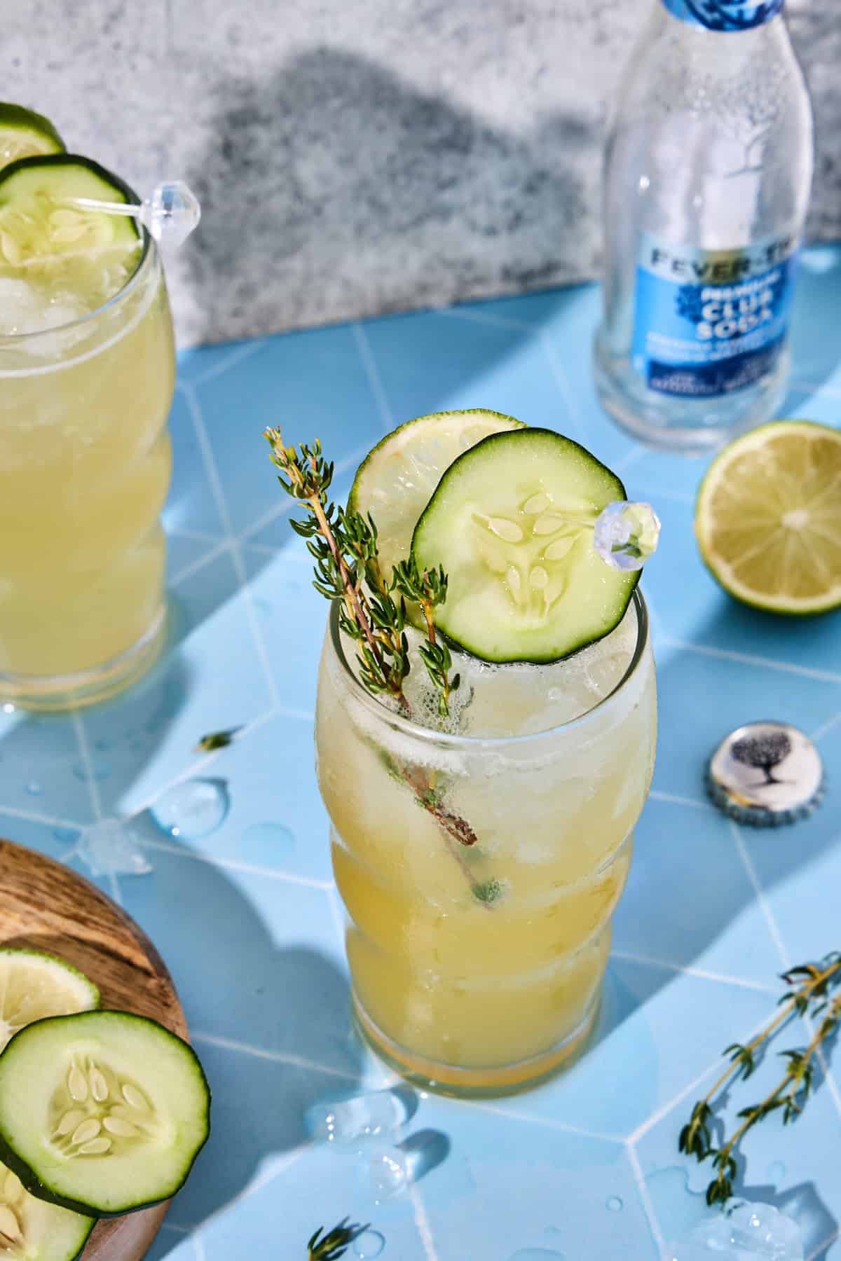 Cucumber gin cocktail served in a glass with cucumber, lime, and thyme sprig garnish.
