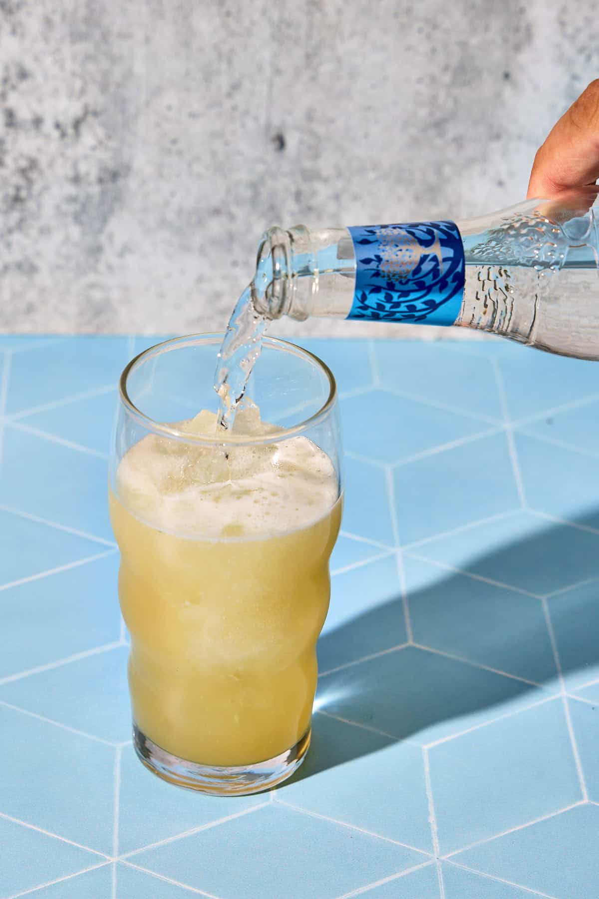 club soda being poured into the cucumber gin cocktail glass