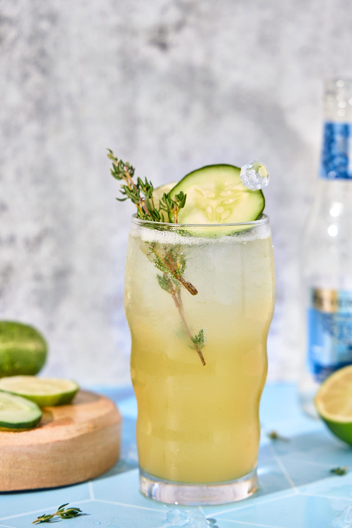 a glass of cucumber cocktail with thyme and lime slice