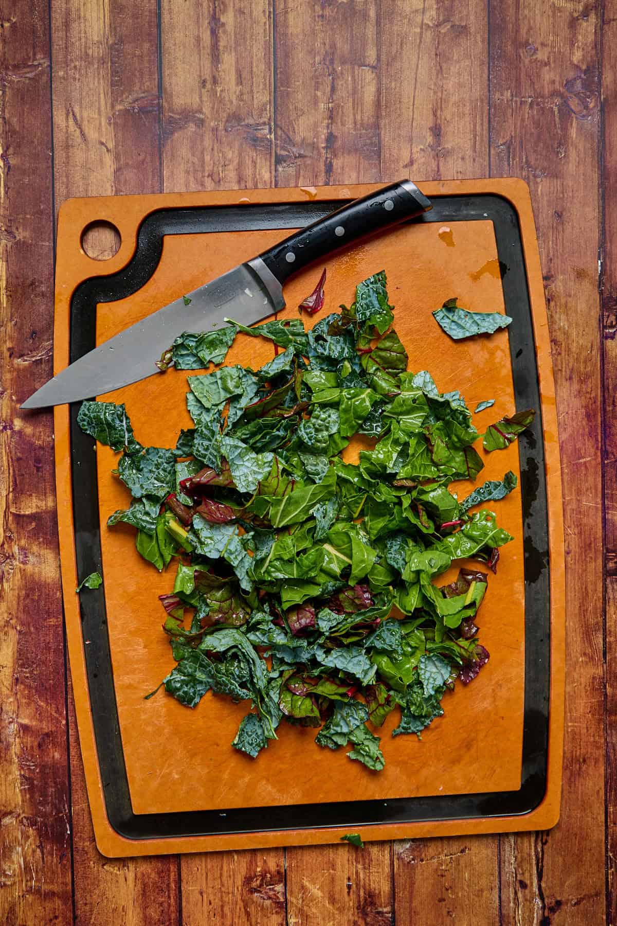 kale and chard chopped on a cutting board with a knife