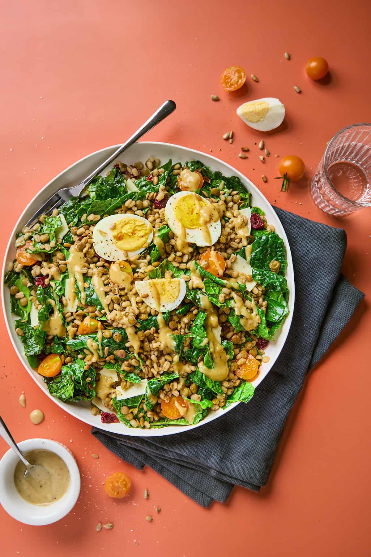 a plate of salad made with kale, lentils, barely, and eggs with dressing