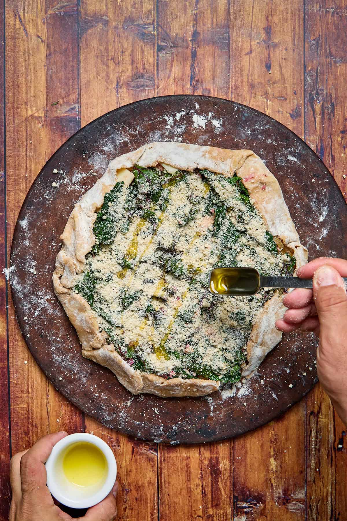 cheese and breadcrumbs being spread over the galette