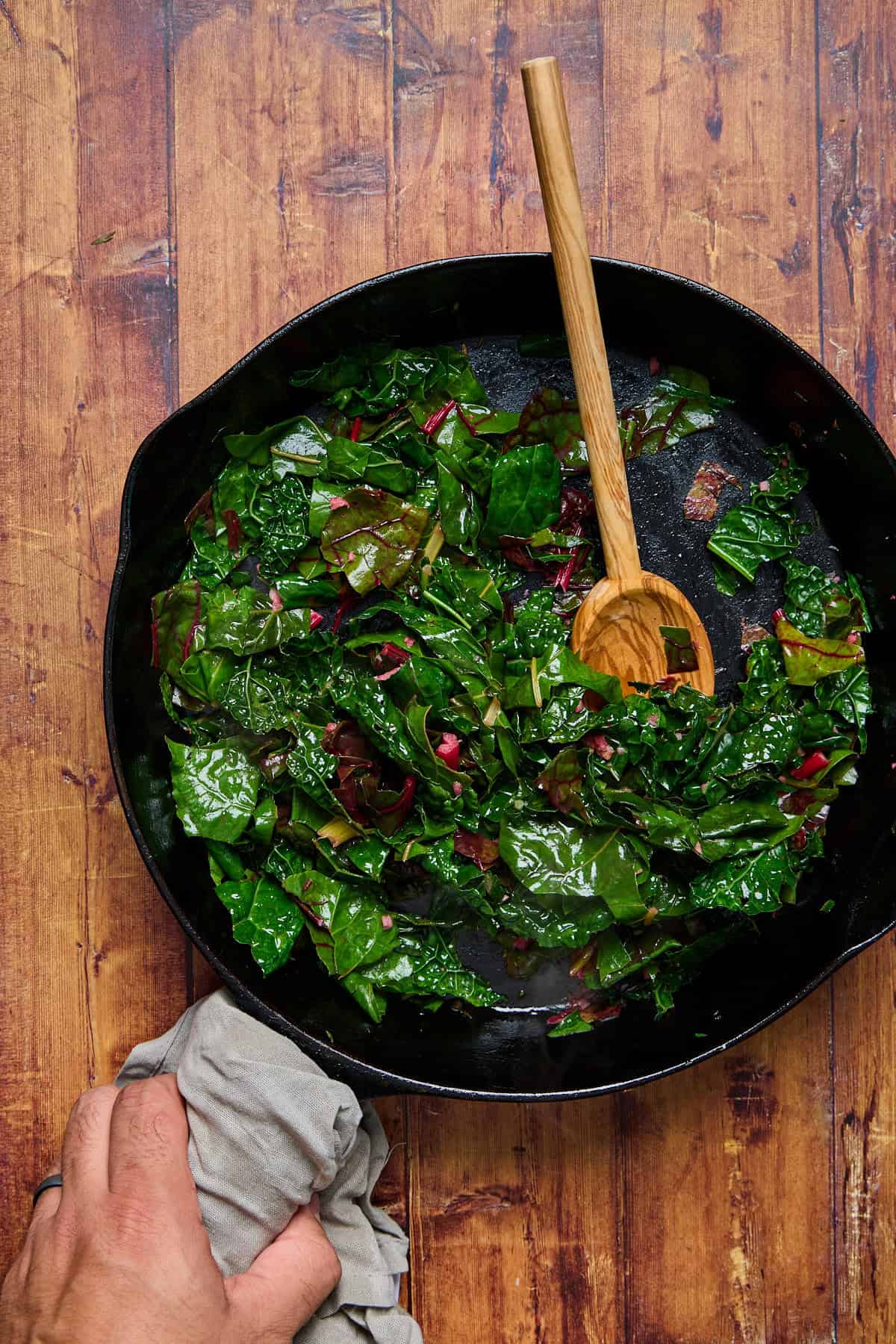 kale and siwss chard being sauteed in a cast iron pan