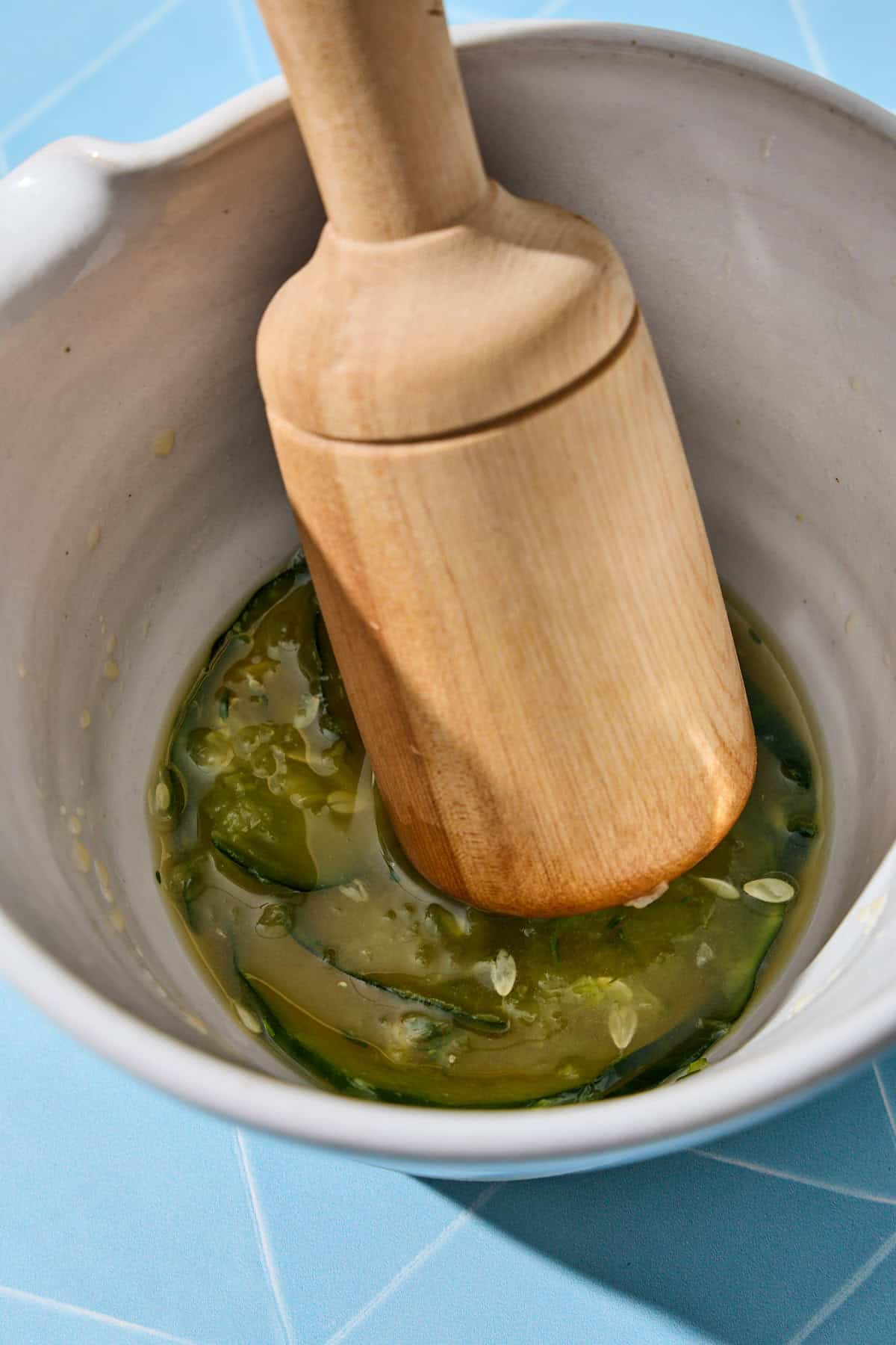 cucumber and ingredients being muddled with a pestle