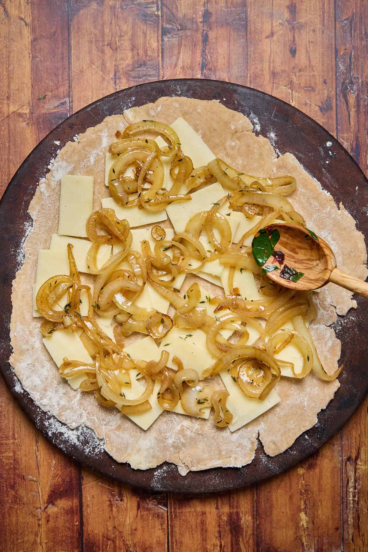 pie dough being layered with cheese and onions