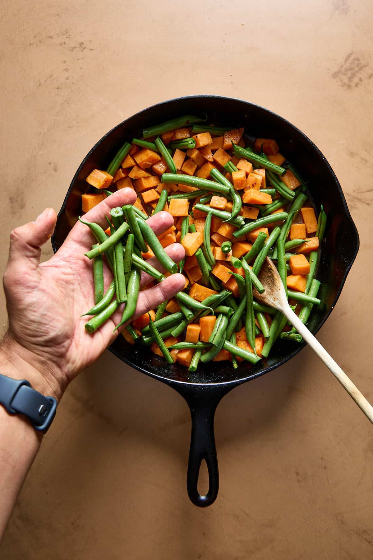 green beans being added to pan of sweet potatoes