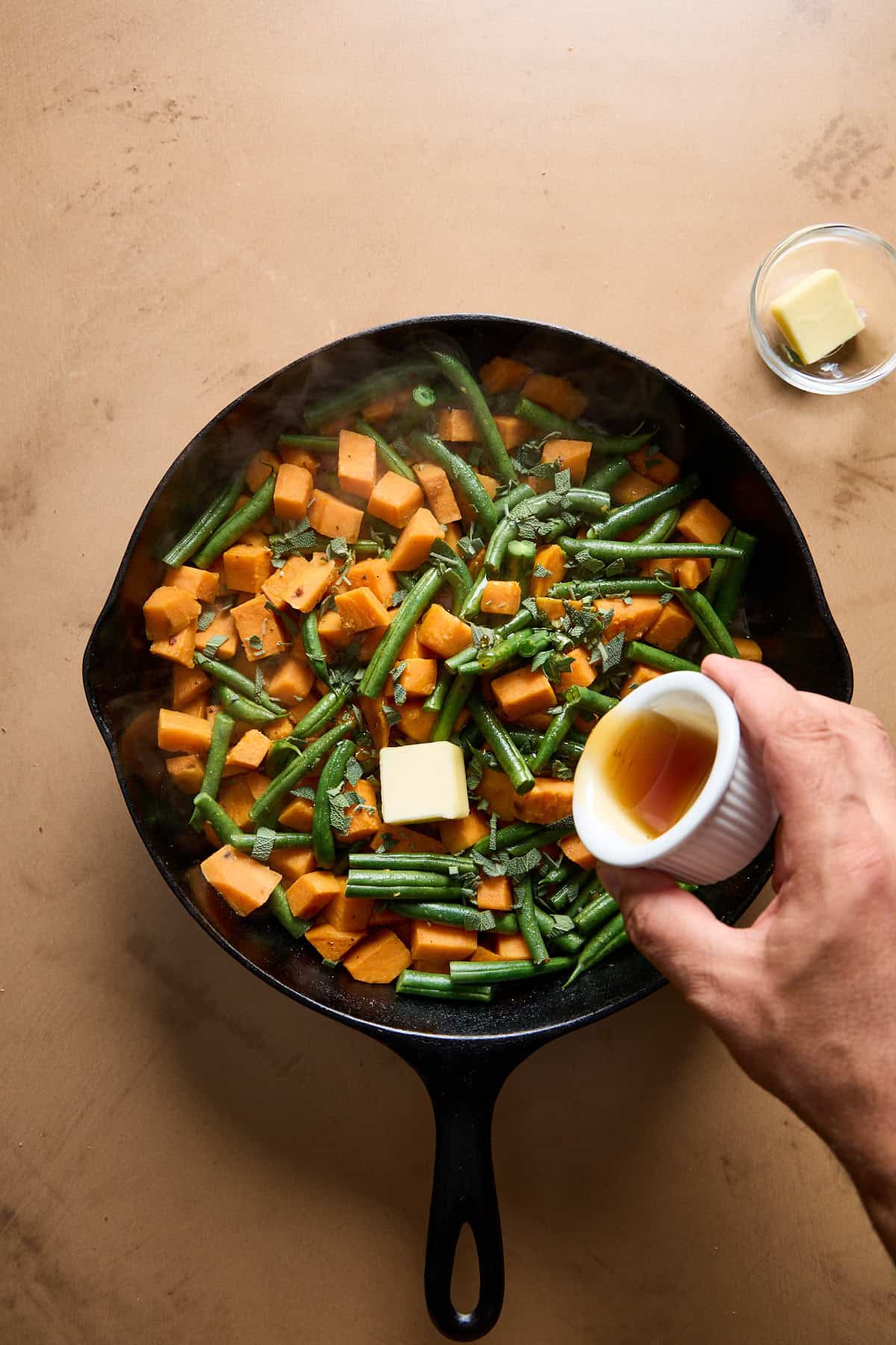 maple syrup and butter being added to beans and sweet potatoes