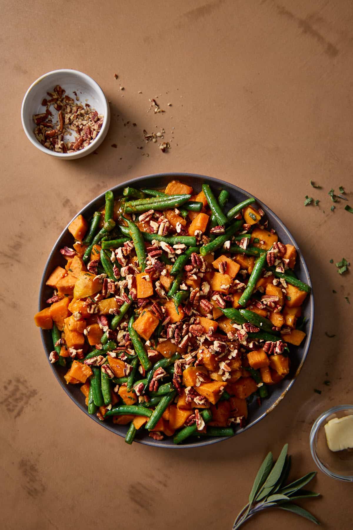 green beans and sweet potatoes on a plate with sage and pecans