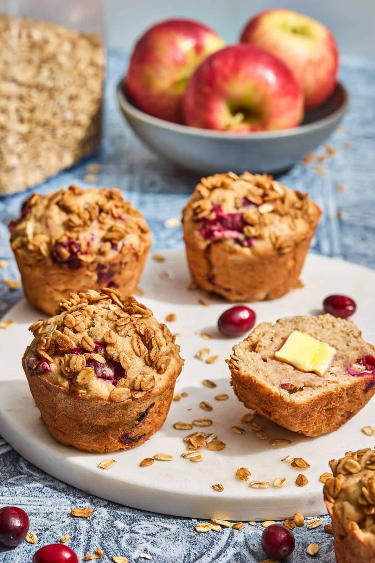 apple cranberry muffins with butter on a countertop with cranberries