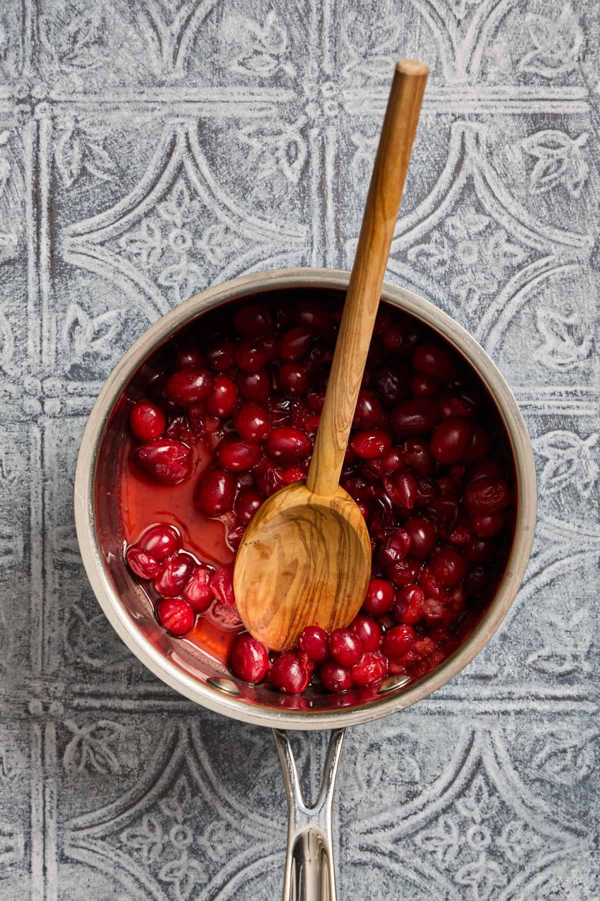 cranberries cooking in a pan with a wooden spoon