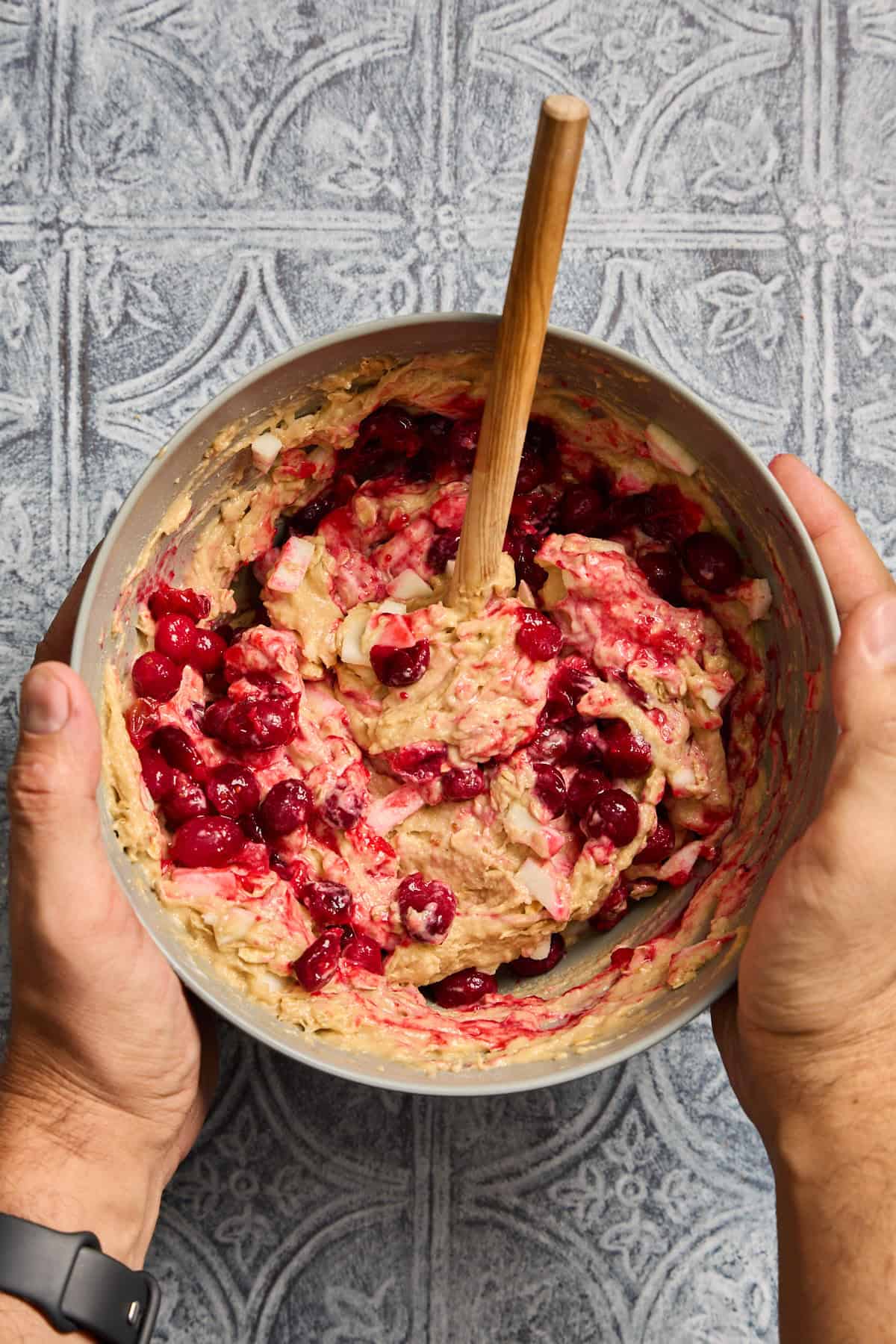 cranberries swirled into a bowl of muffin batter