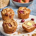several cranberry and apple muffins on a countertop with oats