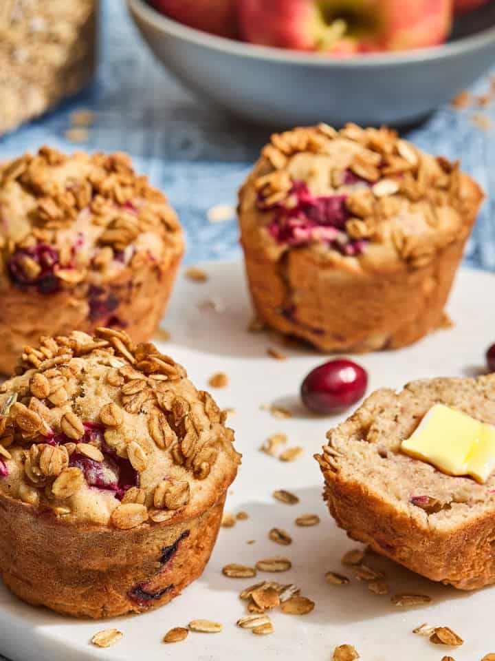 several cranberry and apple muffins on a countertop with oats