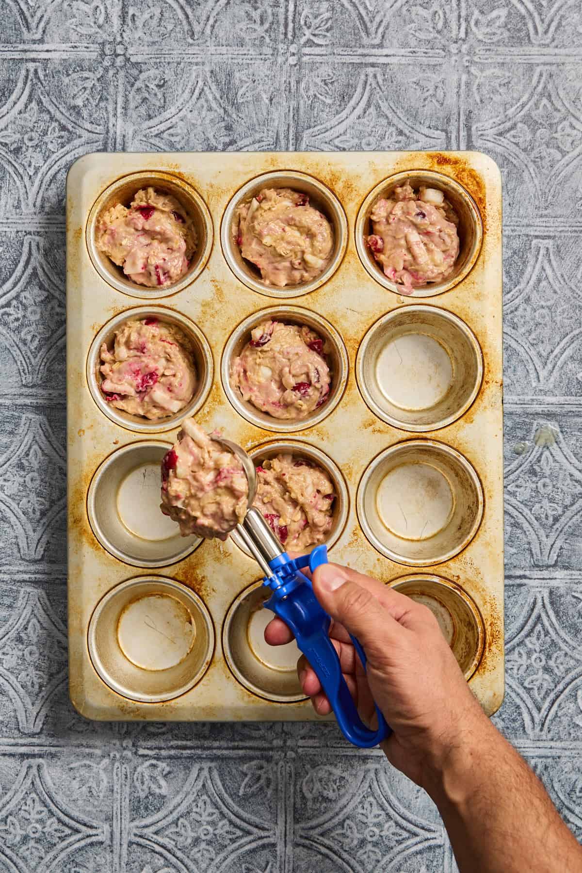 muffin batter being scooped into a muffin tin