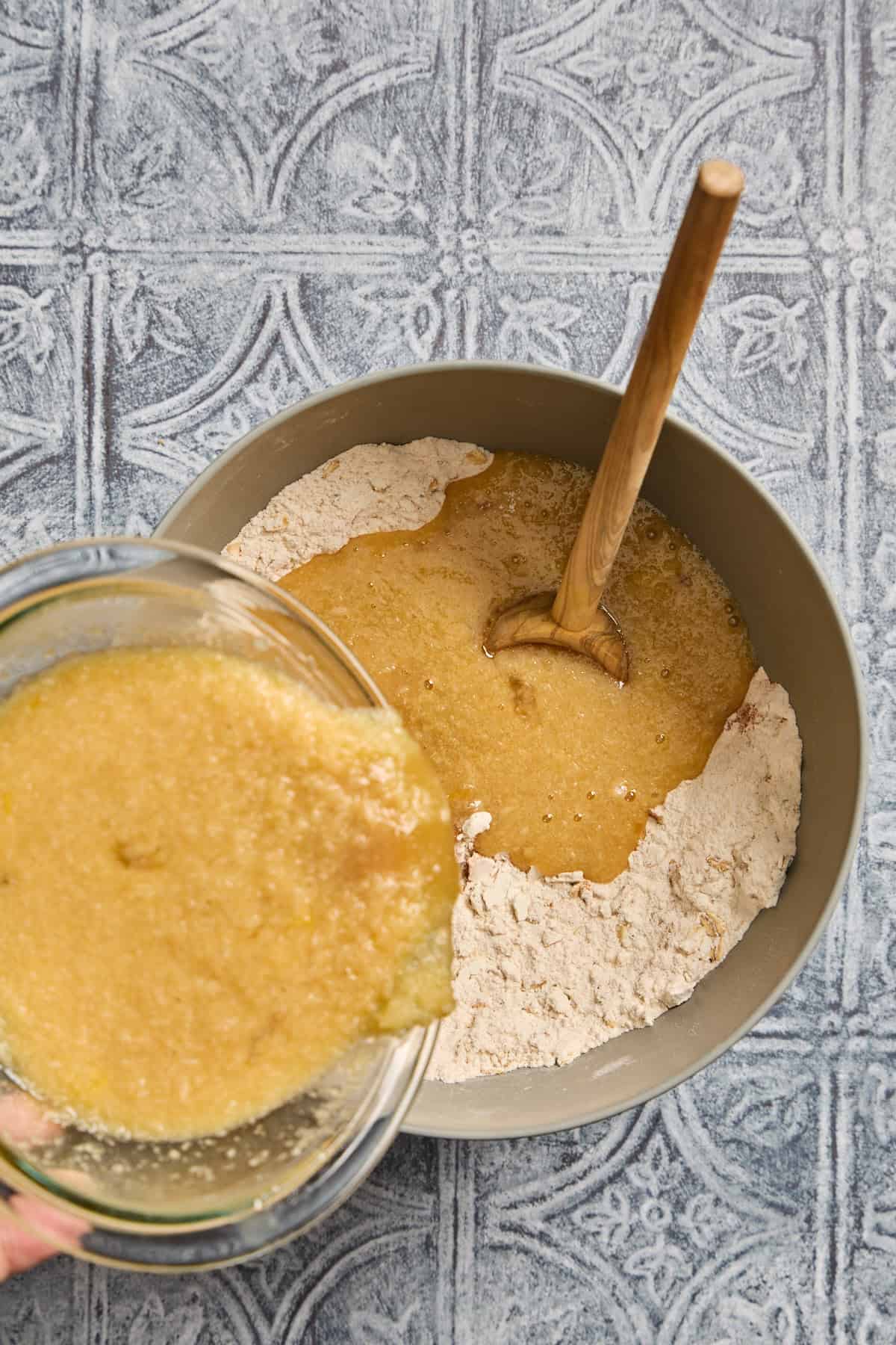 wet ingredients being poured into a bowl of dry ingredients