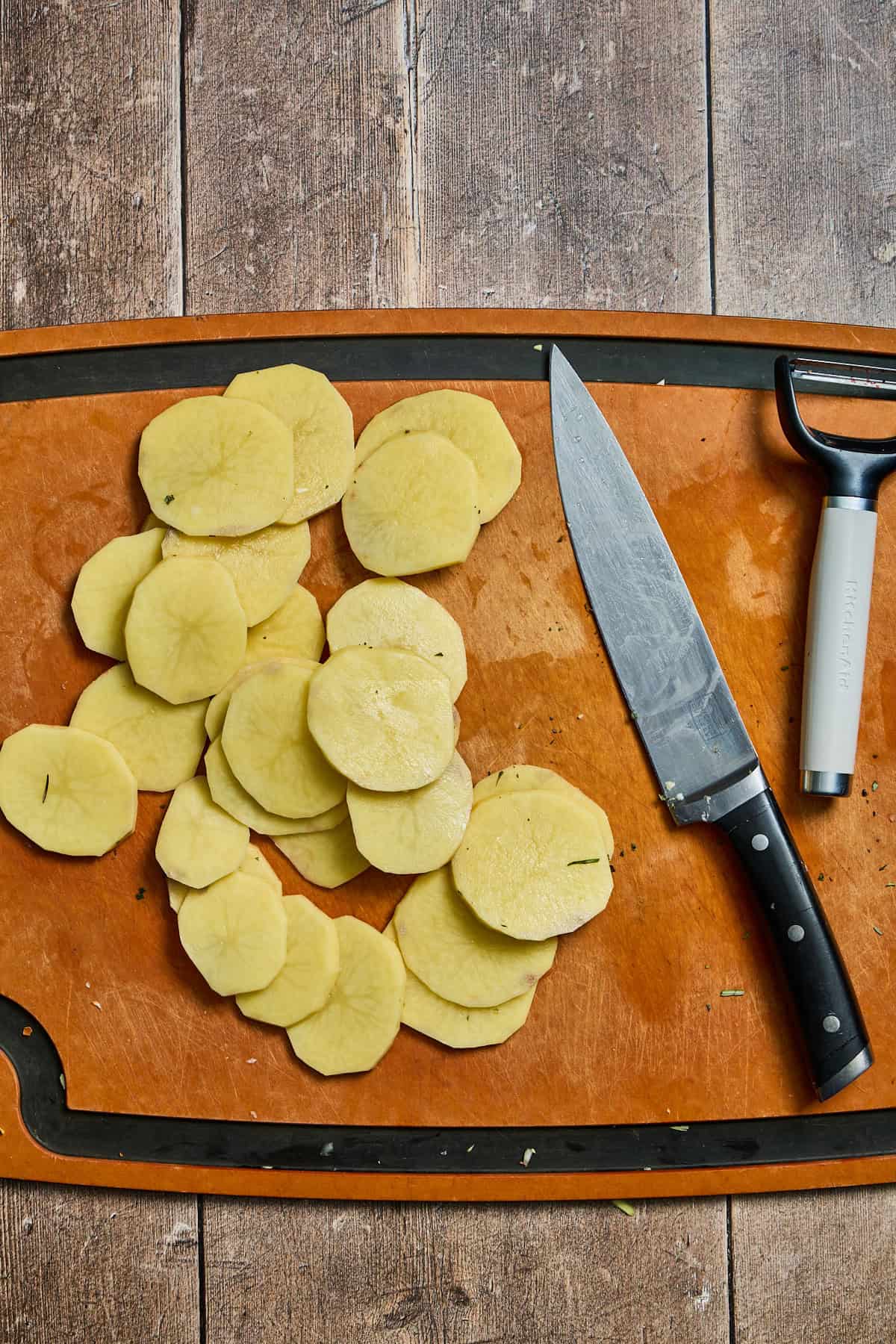 thinly sliced potatoes on a cutting board with a knife