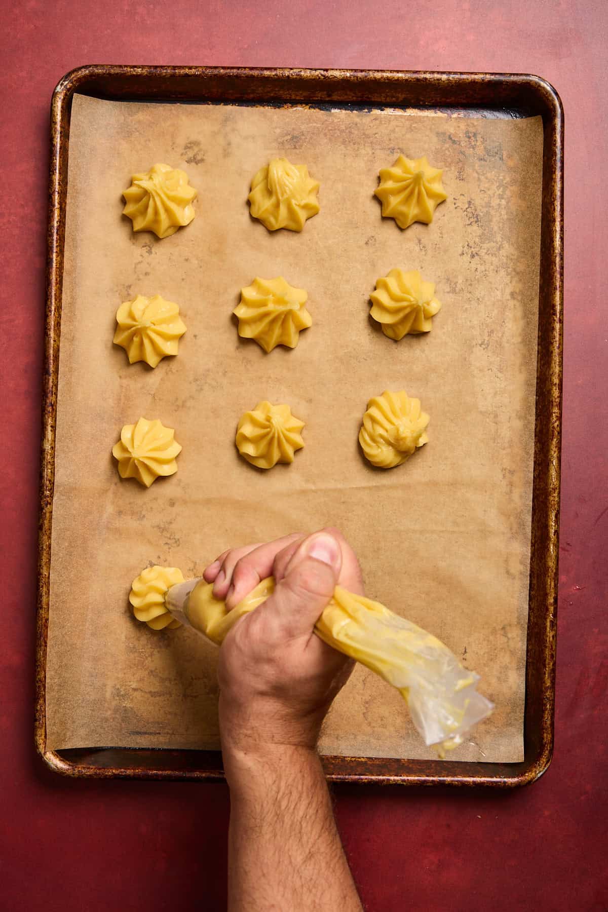 choux pastry being piped onto a baking sheet