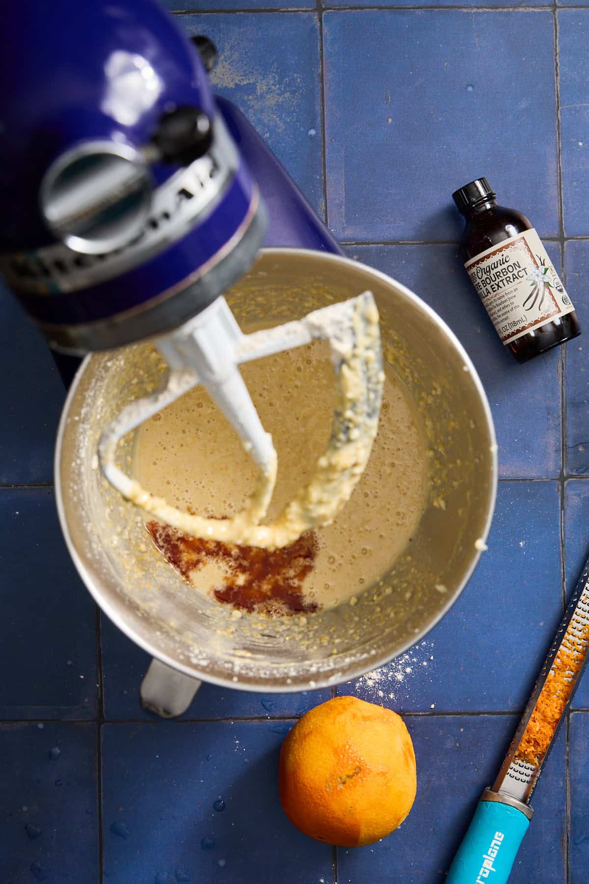 cake batter in a mixer with an orange and vanilla extract bottle