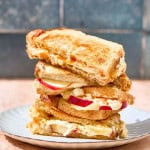 a stack of grilled cheese on a plate with apples