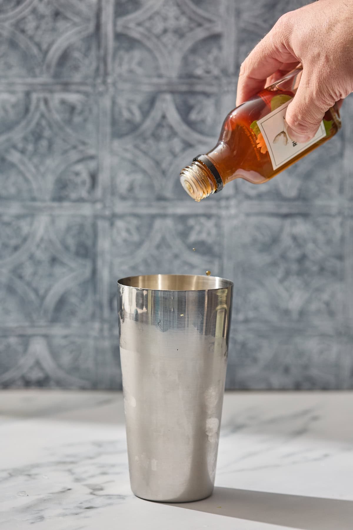 a bottle of bitters being shook into the cocktail