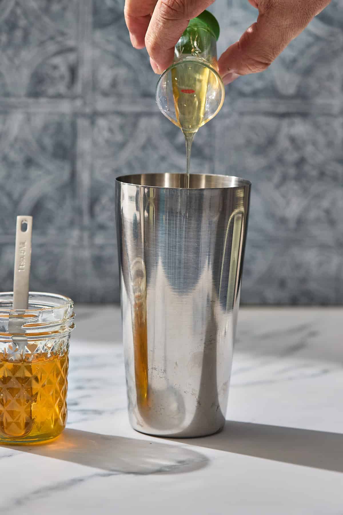 honey being poured into a cocktail shaker