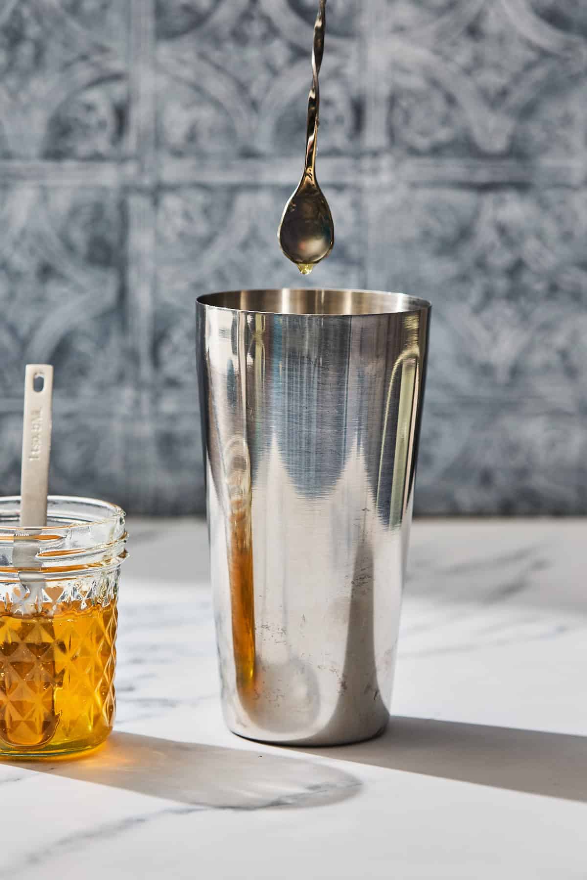 a cocktail stirrer being put in a cocktail shaker