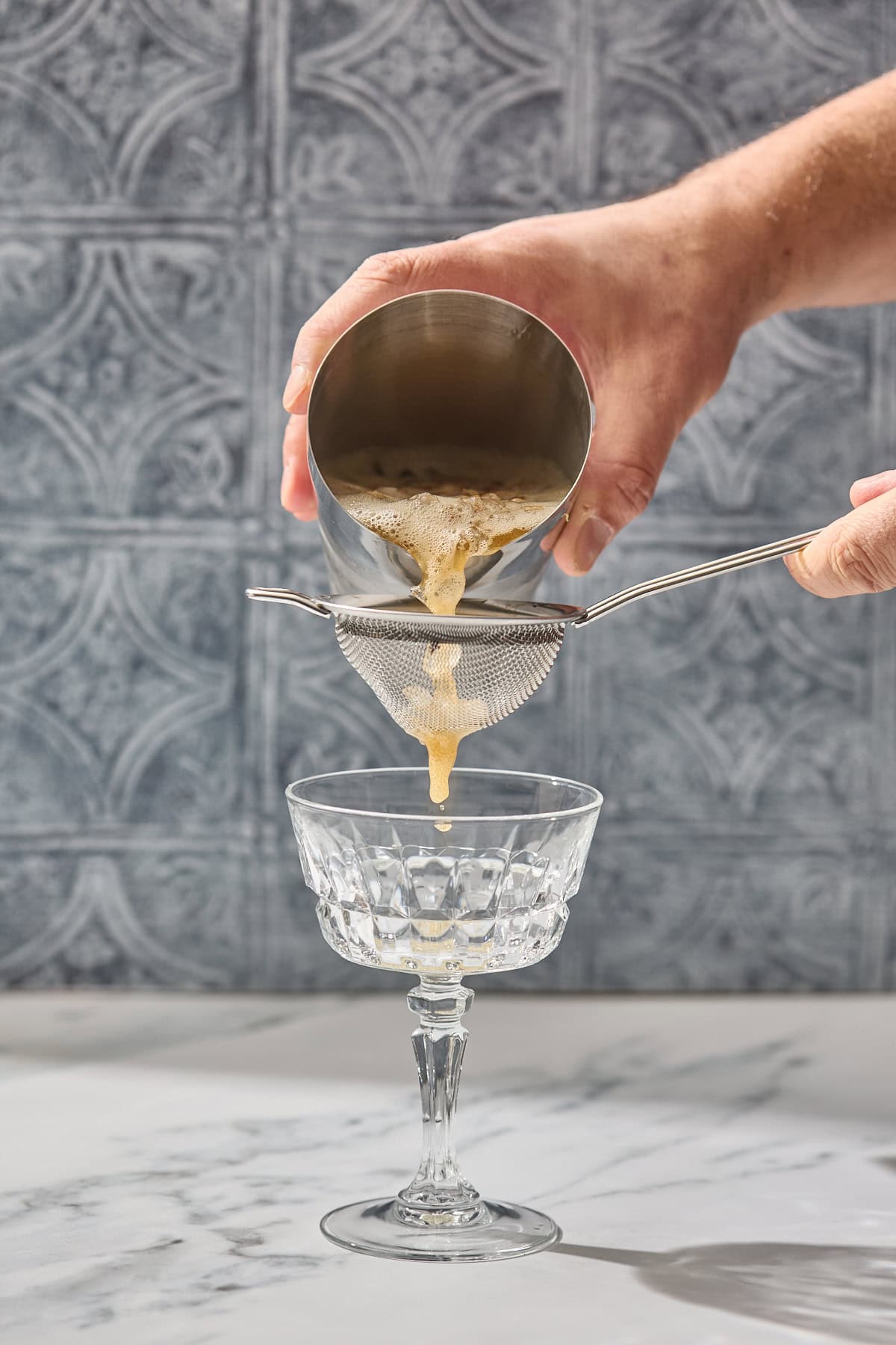 earl grey cocktail being strained into a glass