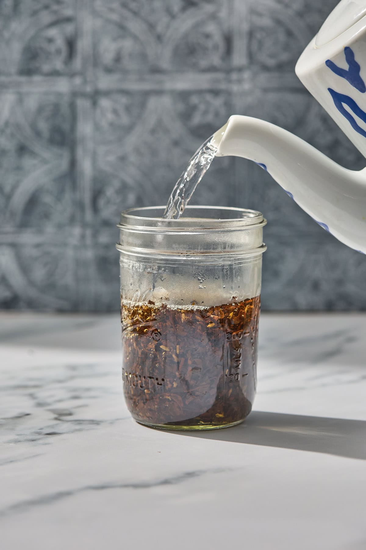 hot water from a kettle being poured into a jar of loose tea