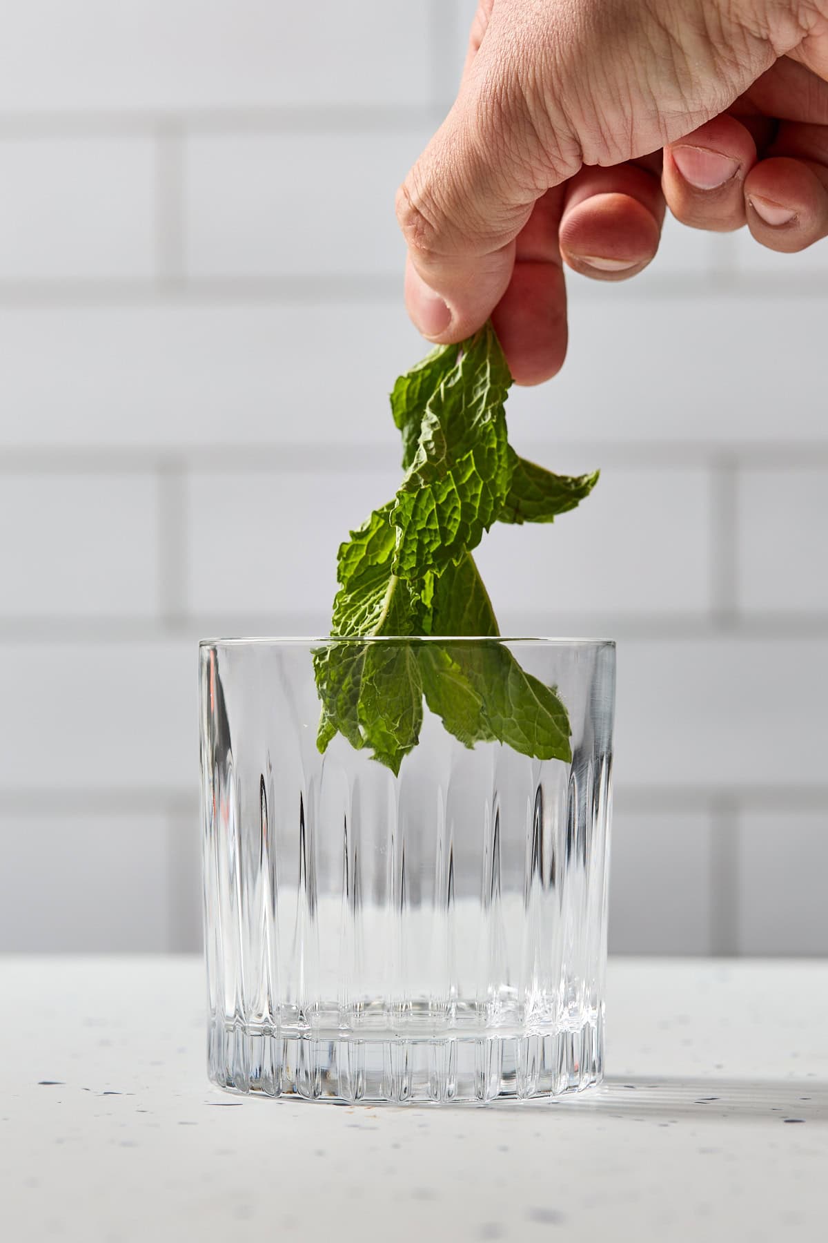 a sprig of mint being added to a glass