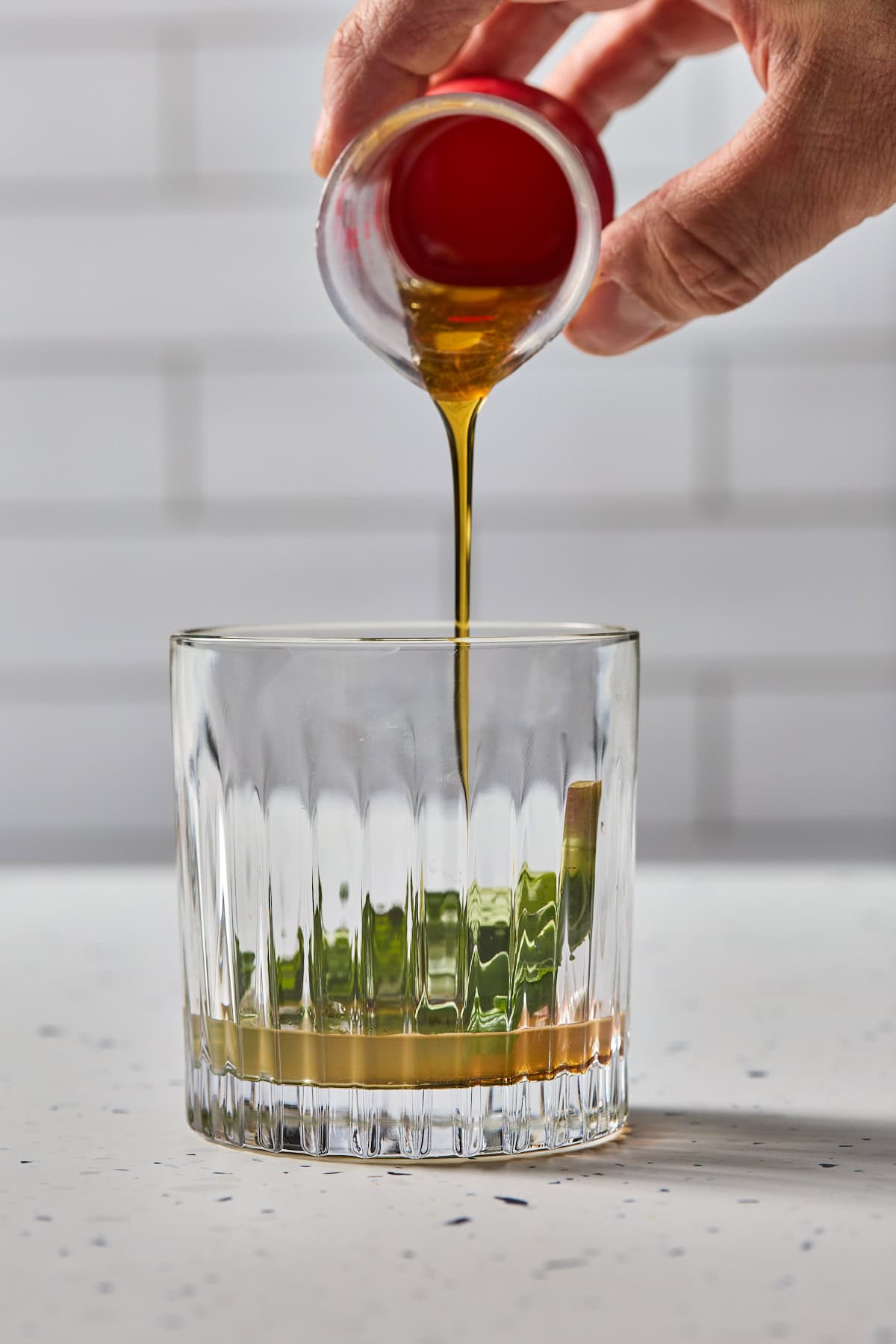 maple syrup being added to a glass of mint