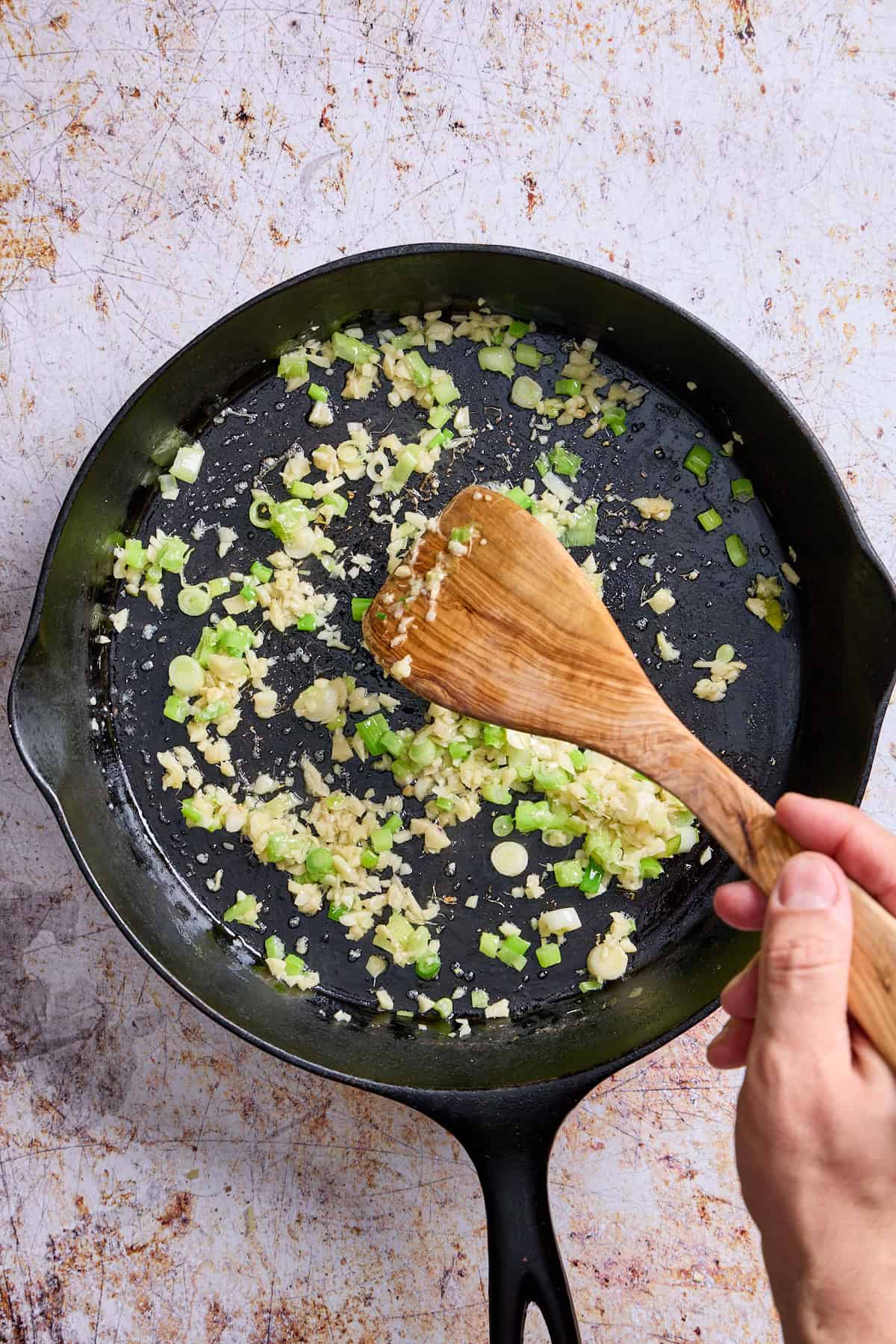 ginger, garlic, and scallions cooking in a pan and being stirred