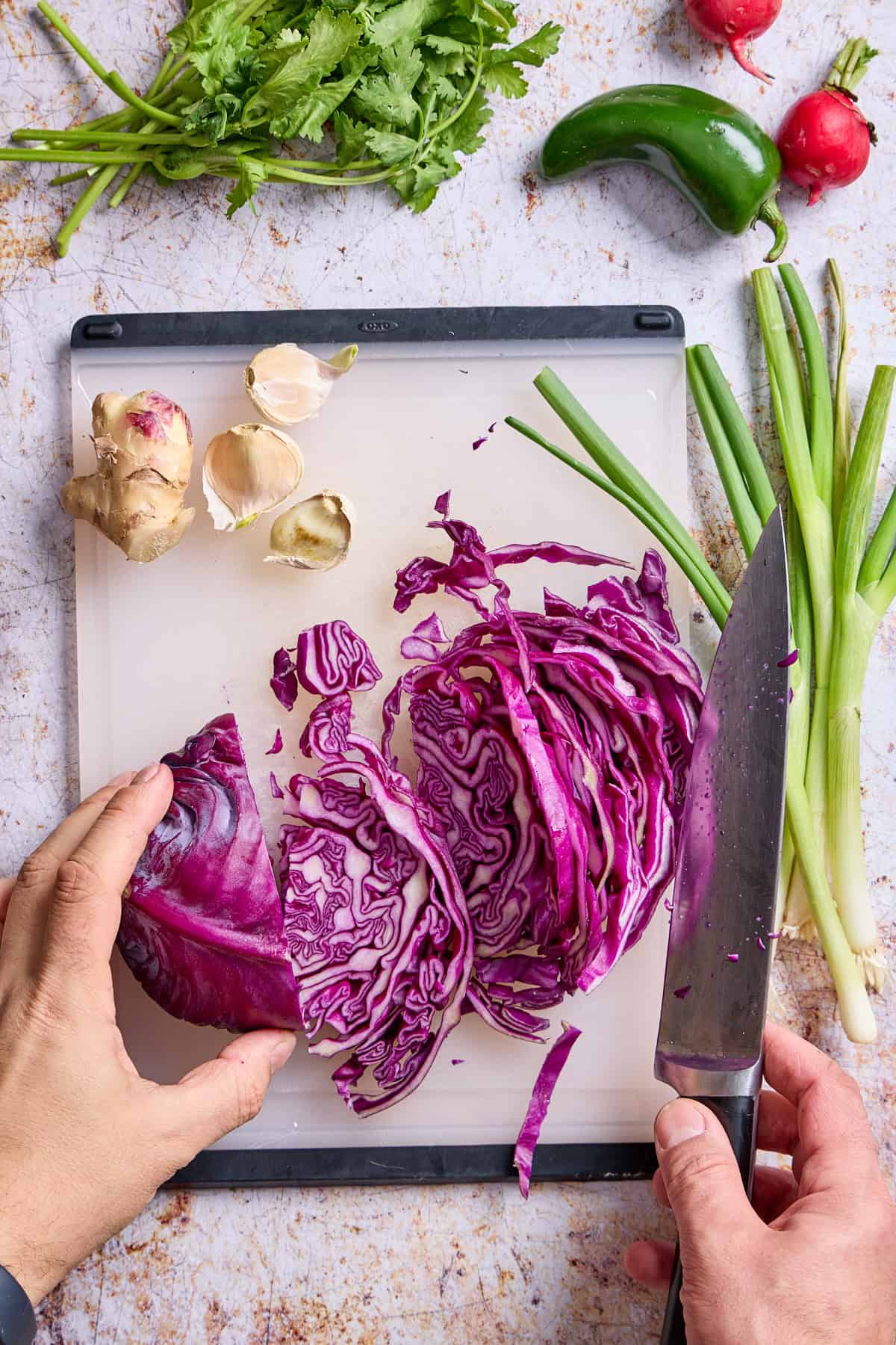 cabbage, scallions, and ginger on a cutting board being chopped