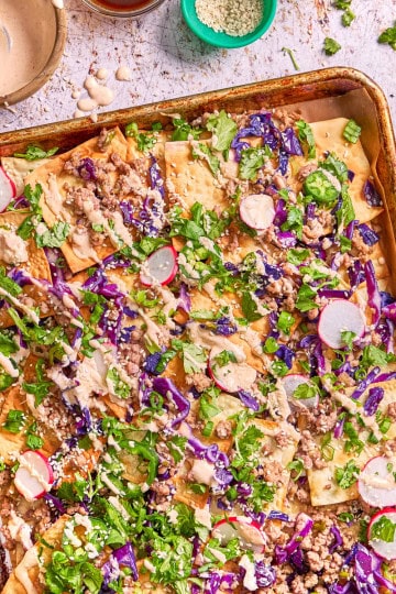 tray of nachos with cabbage, radishes, mayo, and pork