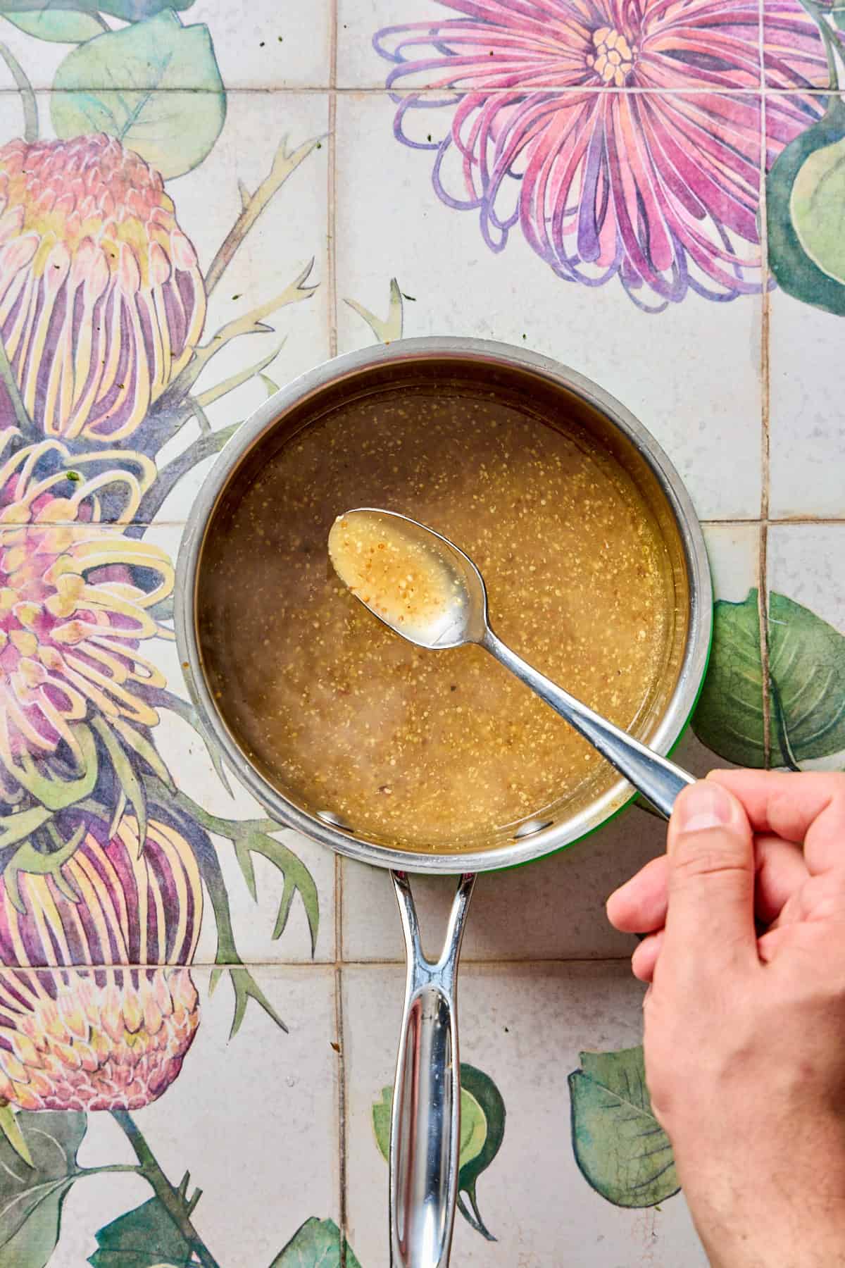 a spoon being held over a pan of lemon sauce