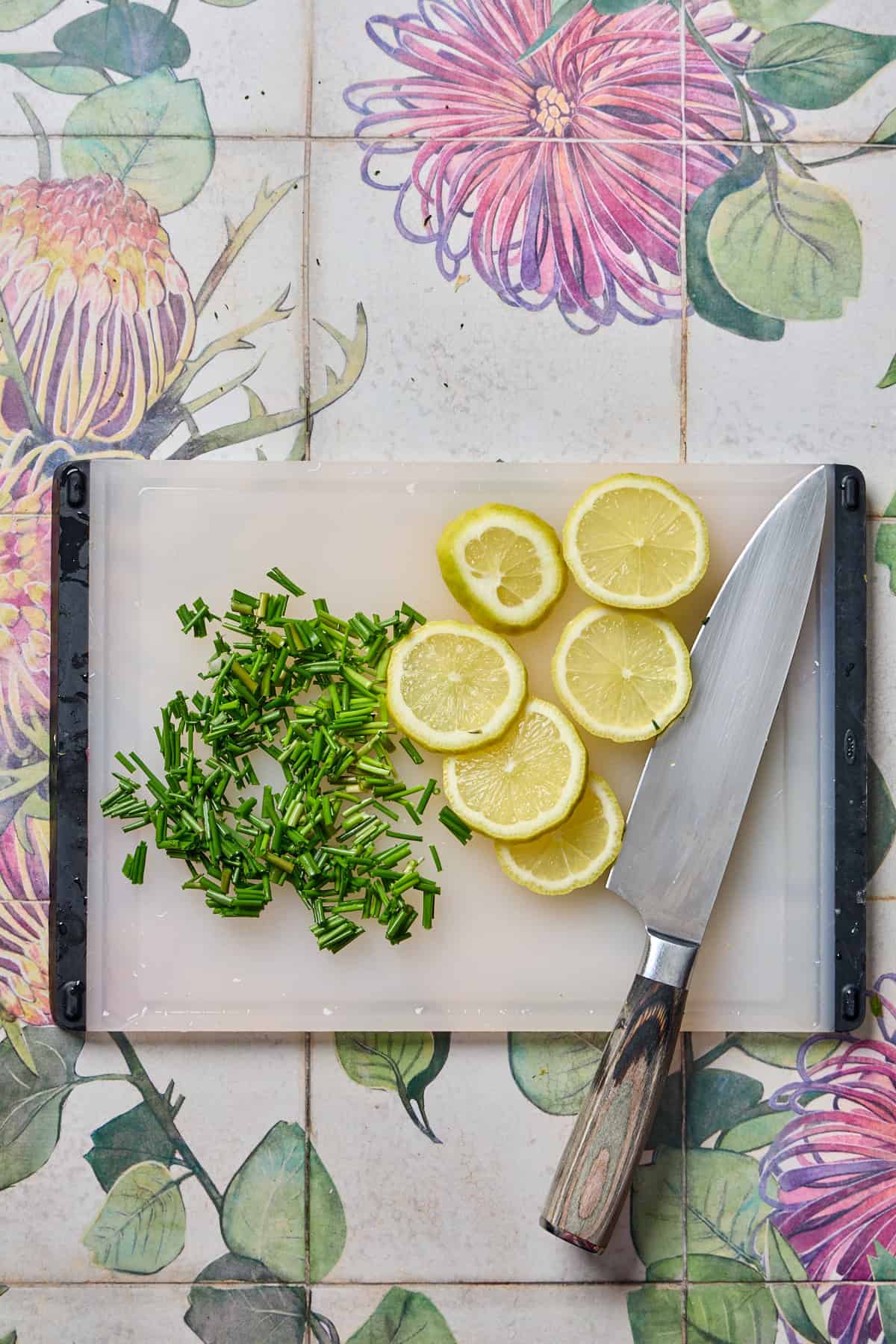 sliced lemons and chopped chives on a small cutting board