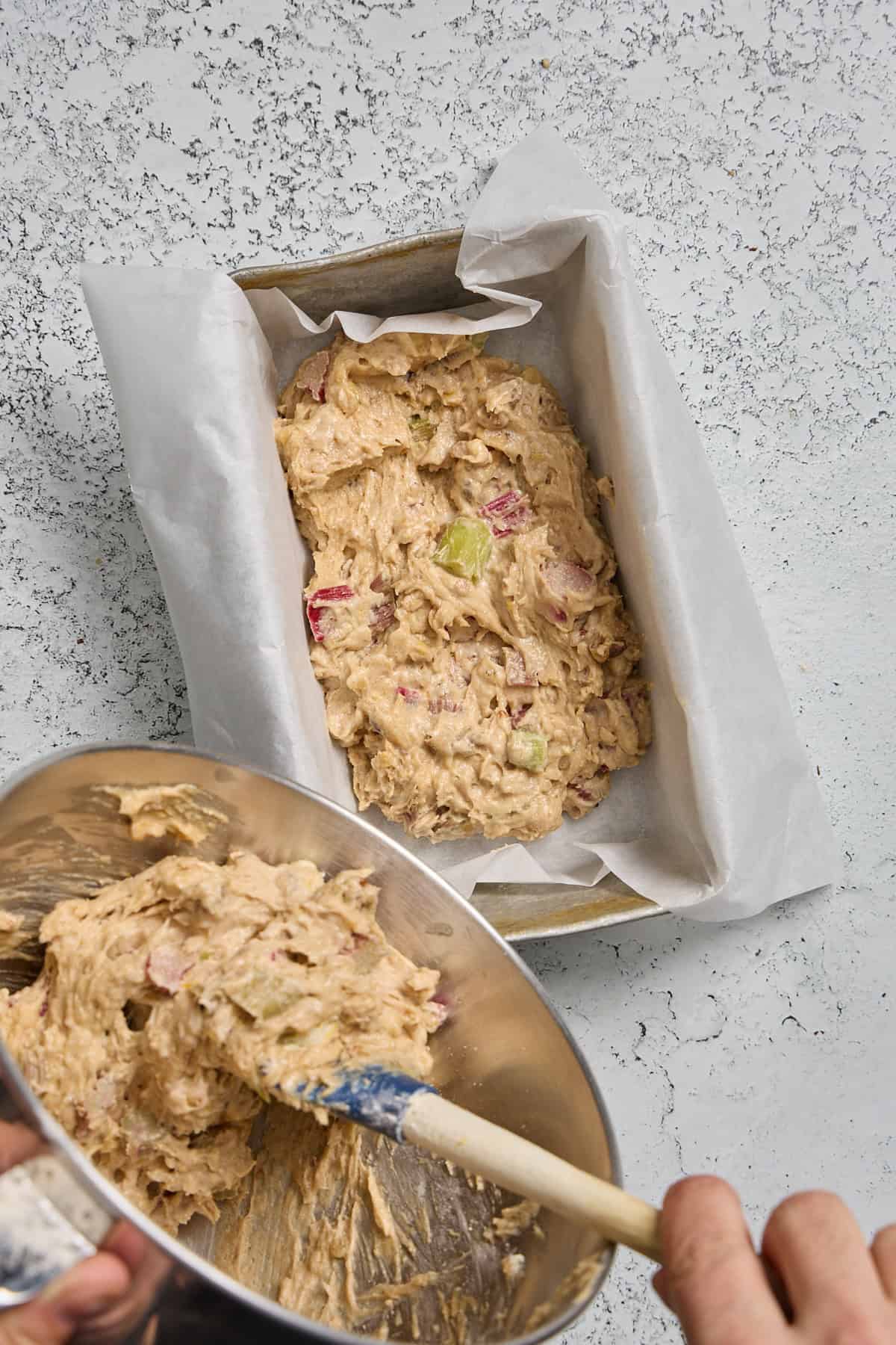 rhubarb bread batter being spooned into a loaf pan