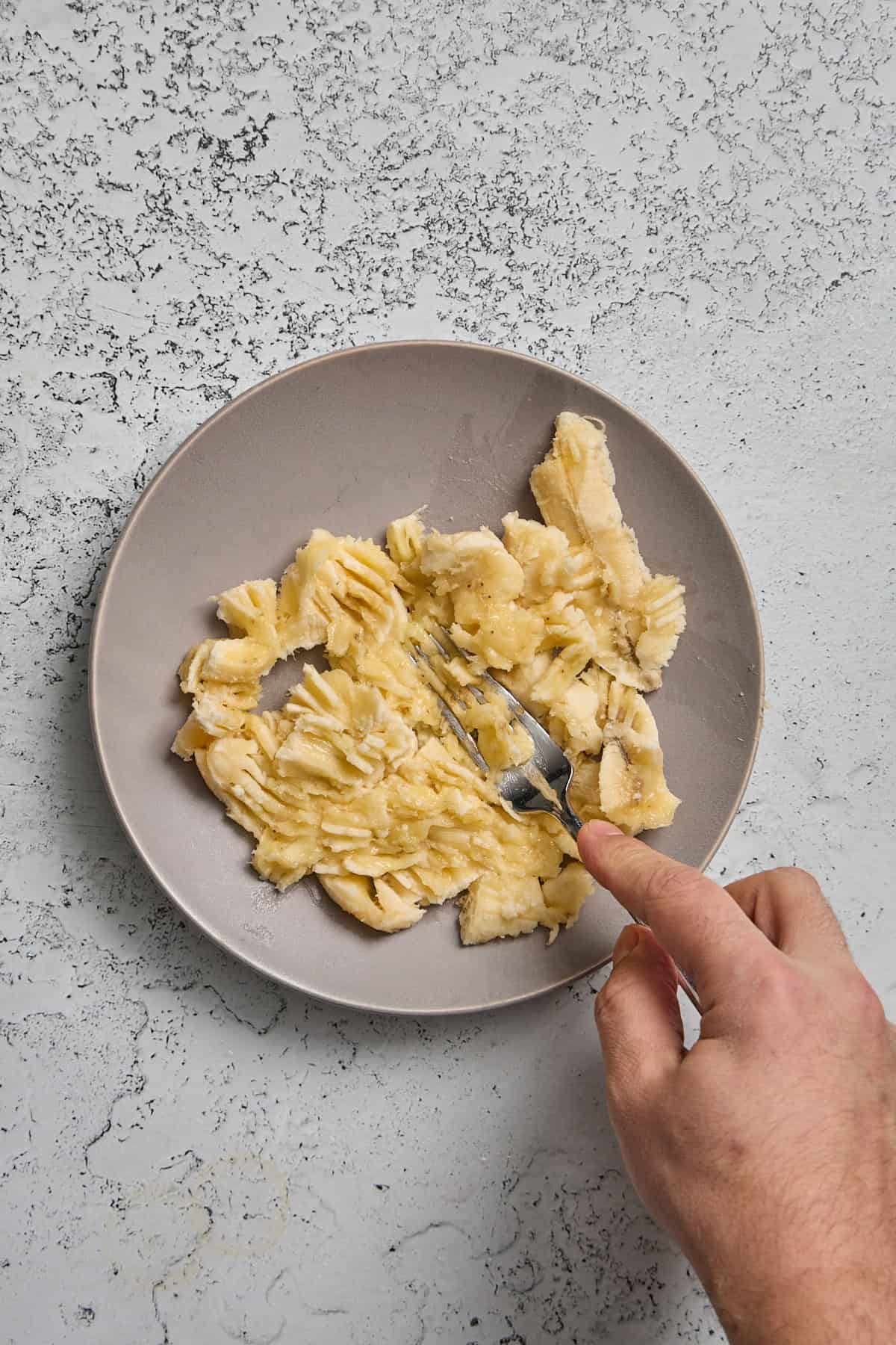 a banana being mashed on a plate with a fork