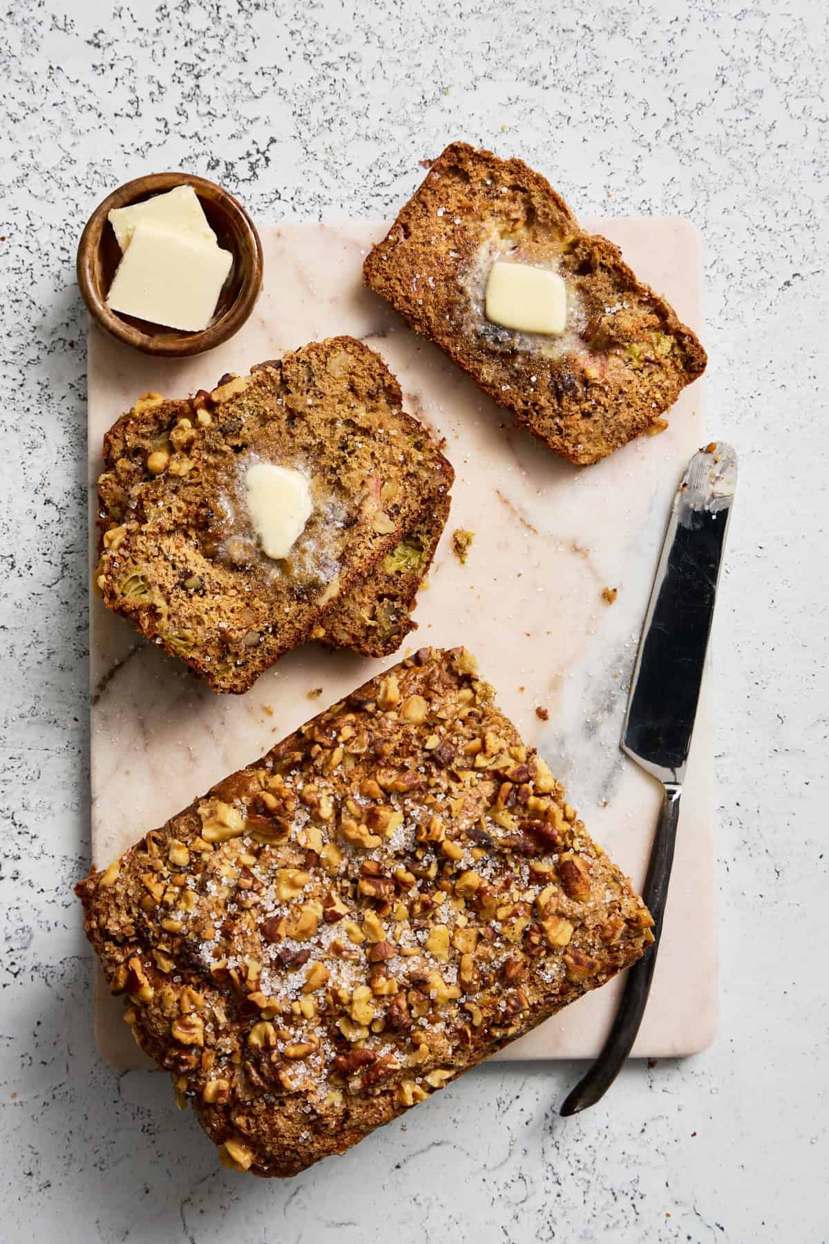 a sliced rhubarb bread on a cutting board with butter