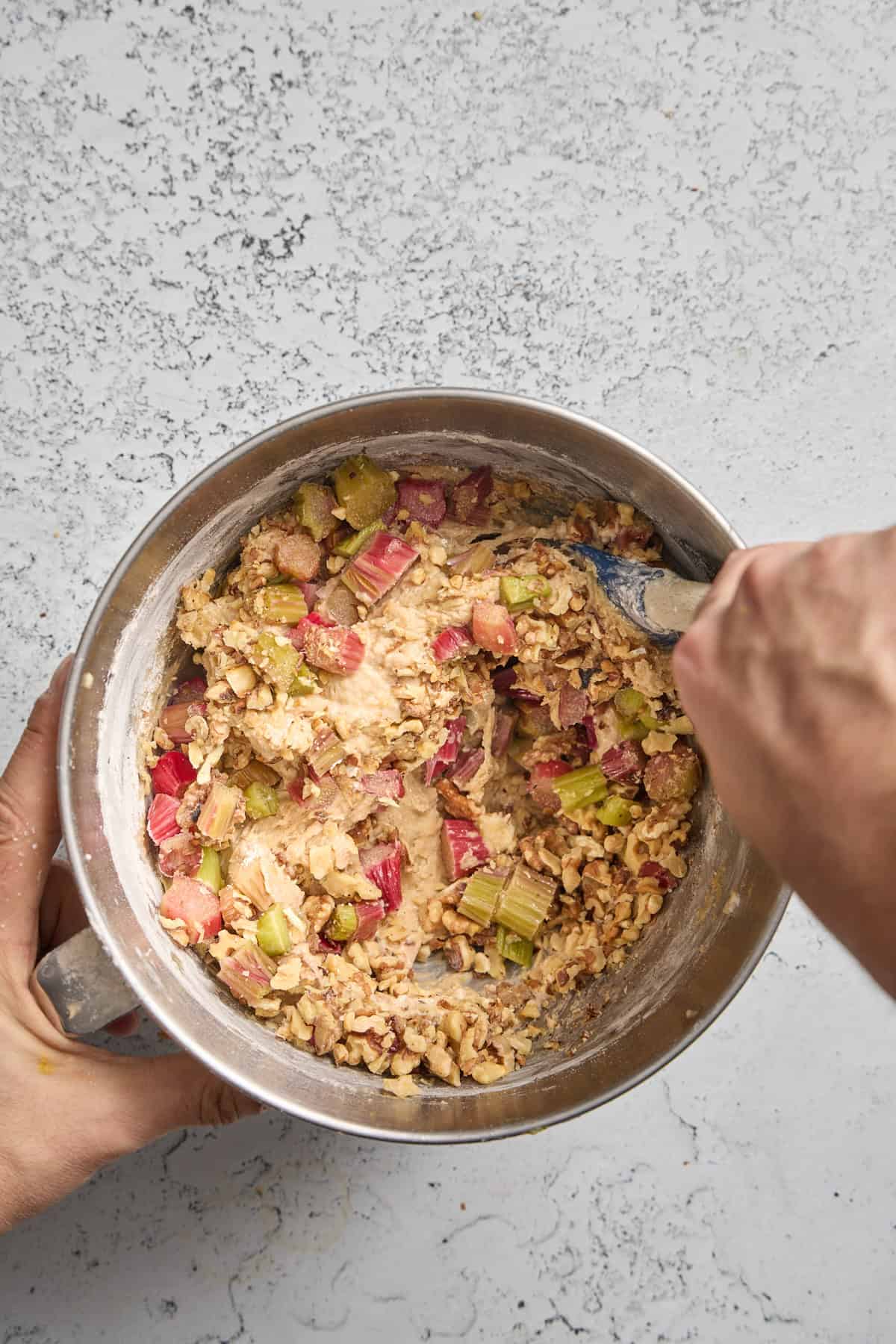 rhubarb being stirred into a bowl of muffin batter