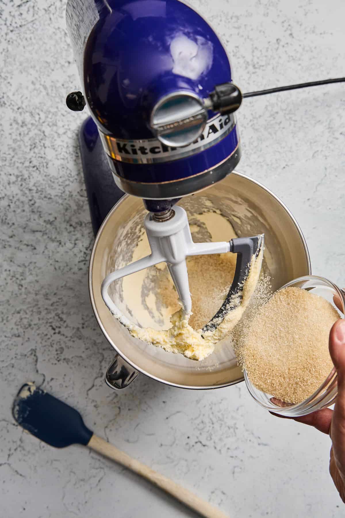butter being beaten in a stand mixer with sugar being added