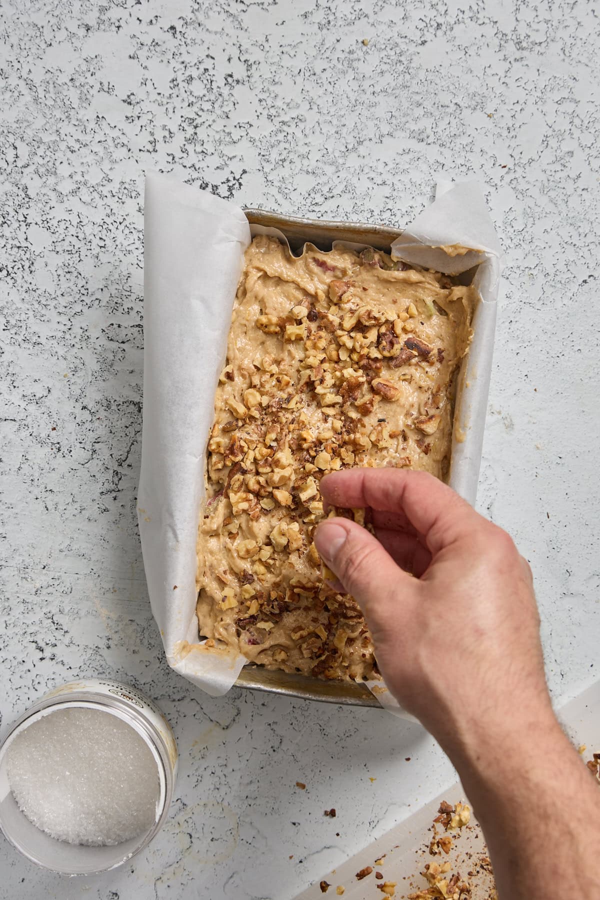walnuts being sprinkled over the bread batter