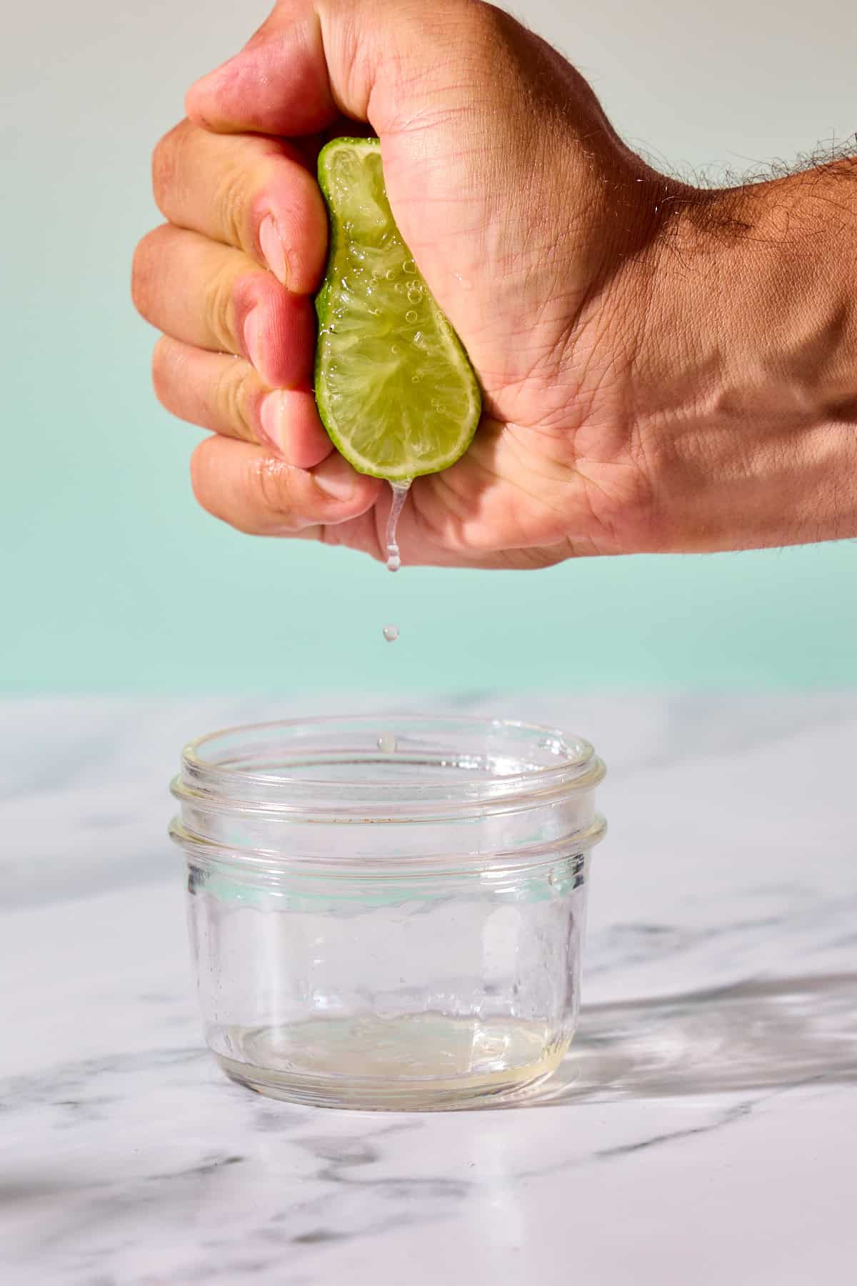 a lime being squeezed over a jar