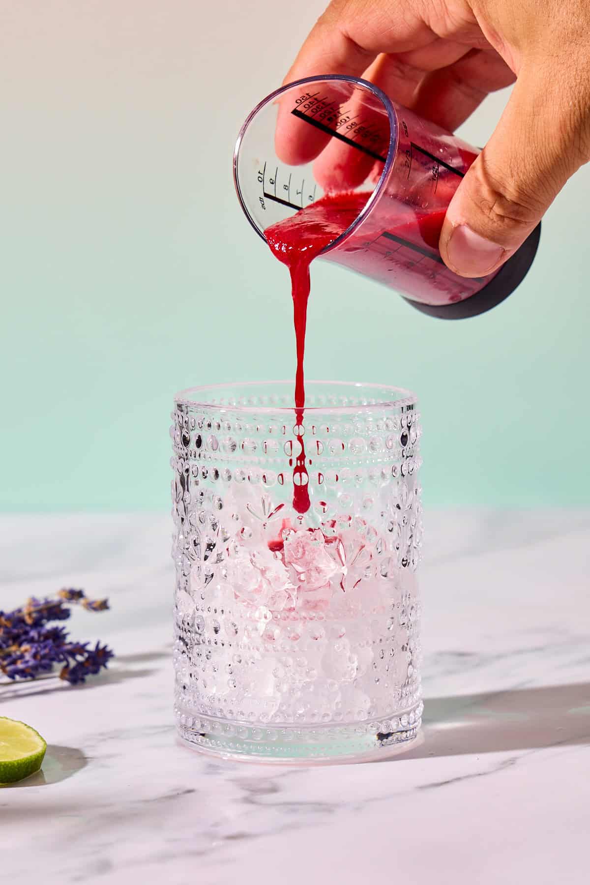 raspberry puree being poured into a glass of ice