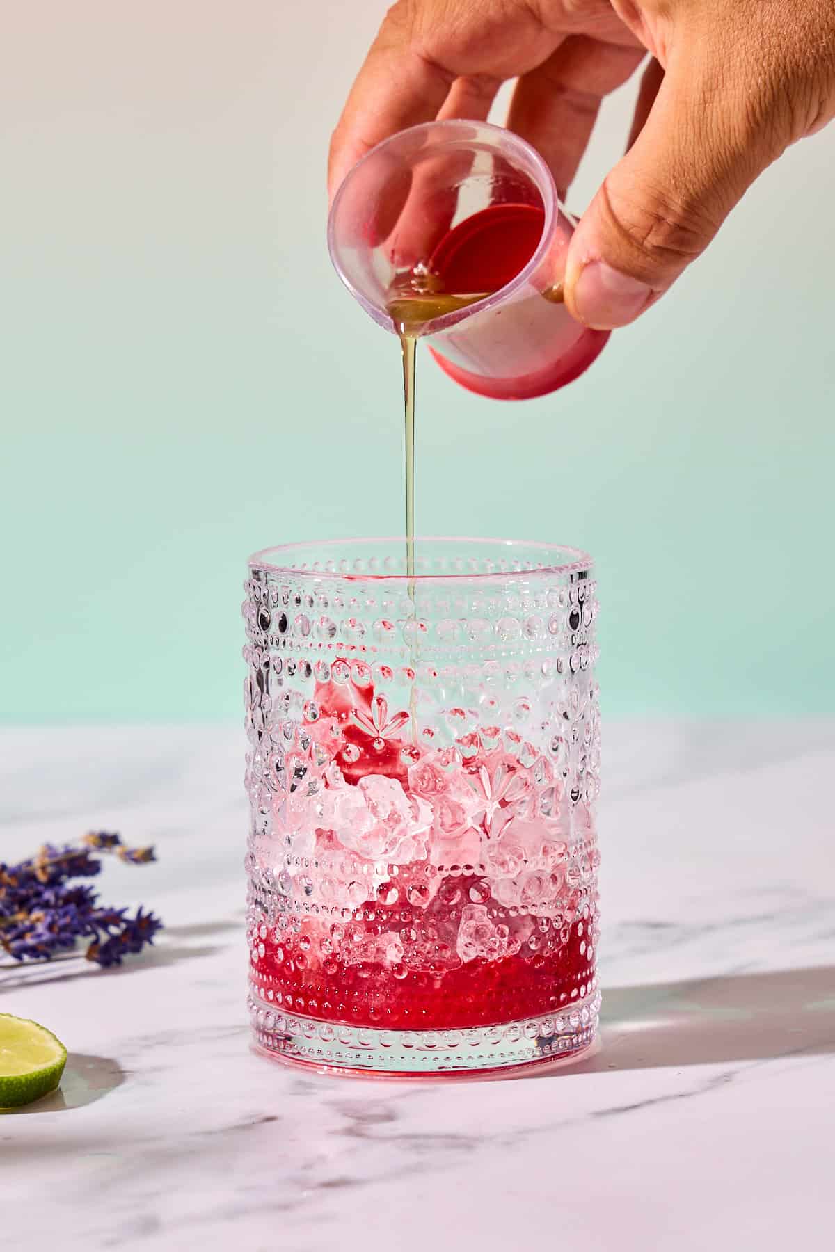 simple syrup being poured into glass of ice