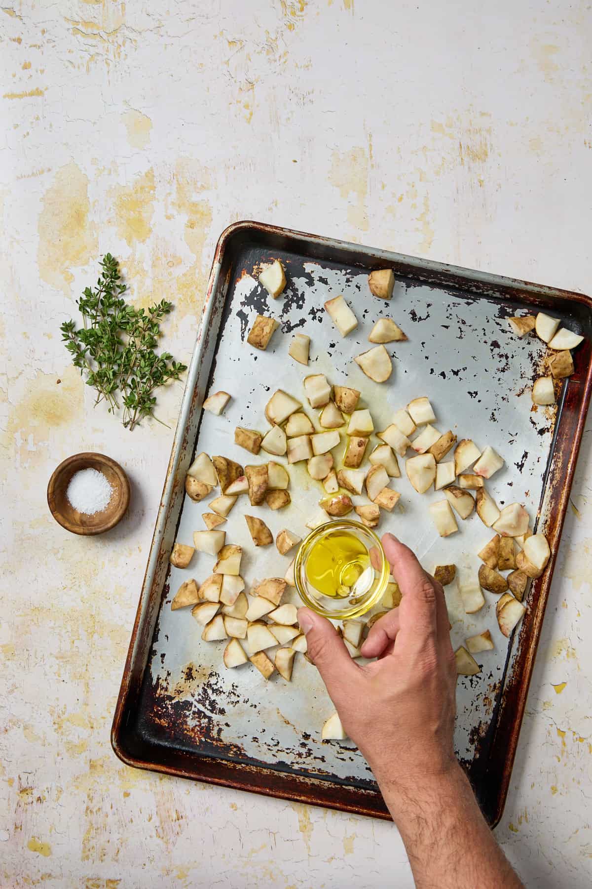 sliced jerusalem artichokes on a pan with olive oil and herbs
