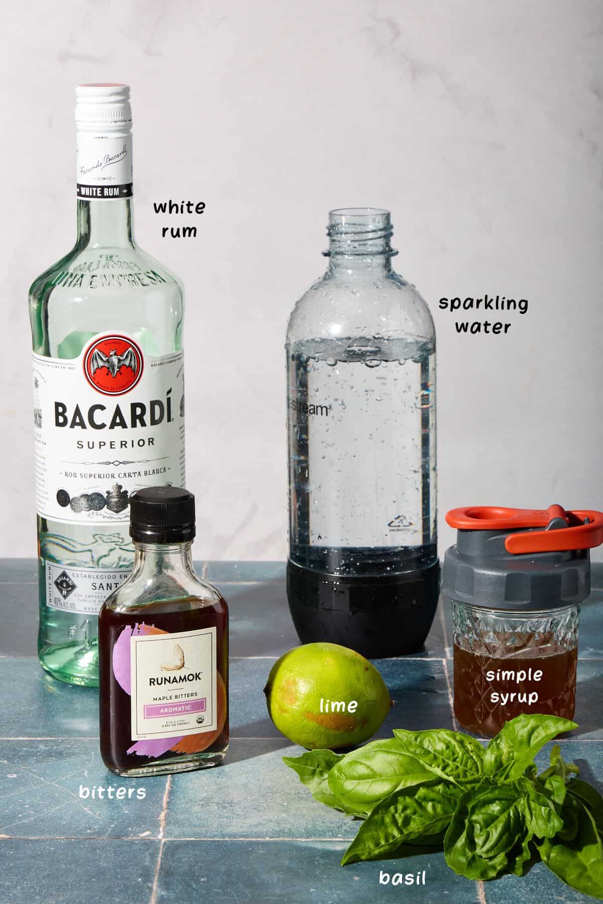 ingredients for making the basil drink on a blue counter with grey background
