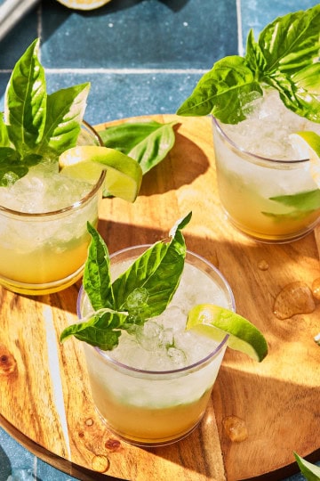 glasses of mojitos with basil on a wooden board and blue counter